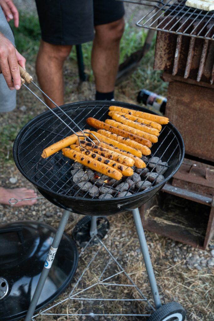 Having a barbecue with hot coals outside, turing sausages on a barbecue or bbq.